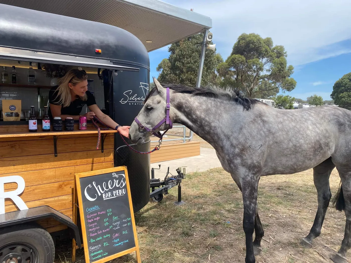 Silverwood Station bartender serving from the restored horse float as a grey horse looks on